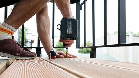 Handwerker: Ein Balkon wird mit Holzbohlen bestückt, sie werden mit Schrauben fixiert