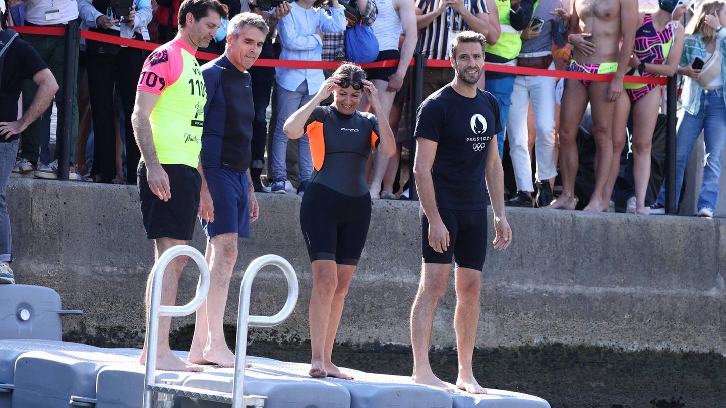 Vor Olympia: Ab in die Seine: Die Pariser Bürgermeisterin Anne Hidalgo (2.v.r.) und Olympia-OK-Chef Tony Estanguet (r.) sind bereit für ein Wagnis: ein Bad in trüben Fluten des Flusses. Im Hintergrund sind zahlreiche Medienvertreter und Schaulustige zu sehen, die die PR-Aktion verfolgen Ab in die Seine: Die Pariser Bürgermeisterin Anne Hidalgo (2.v.r.) und Olympia-OK-Chef Tony Estanguet (r.) sind bereit für ein Wagnis: ein Bad in trüben Fluten des Flusses. Im Hintergrund sind zahlreiche Medienvertreter und Schaulustige zu sehen, die die PR-Aktion verfolgen