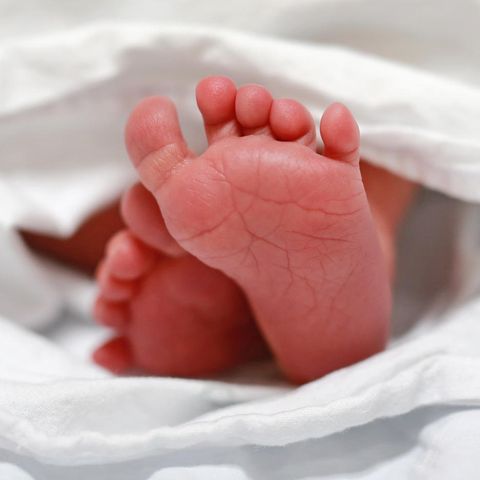 Zwei Babyfüße ragen aus einem weißen Tuch heraus