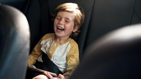 Ein Junge lacht auf der Rückbank eines Autos