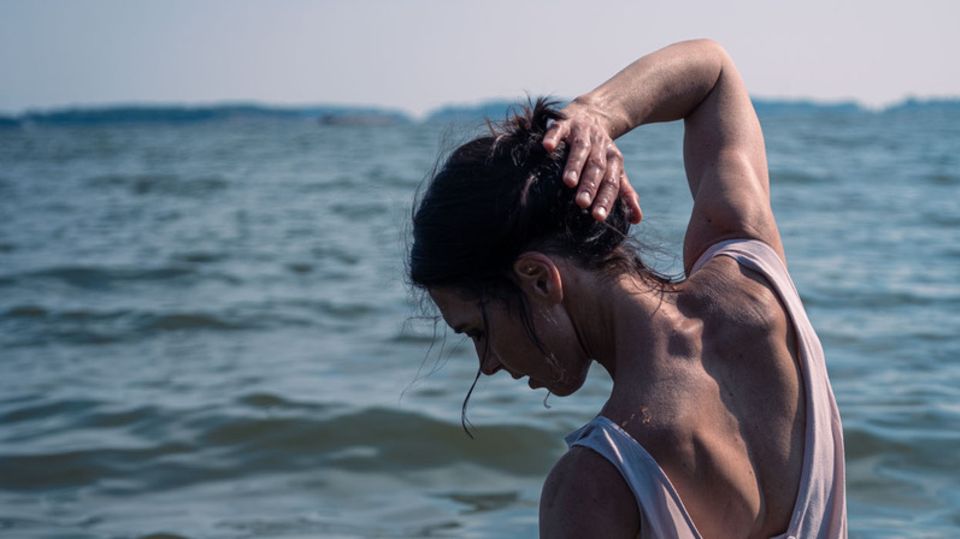 Eine Frau von hinten, die im Wasser steht. Es ist Autorin Hanna Brotherus, die einen Roman über Essstörungen schrieb