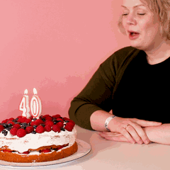 40 werden: Eine Frau pustet Kerzen auf einem Kuchen aus