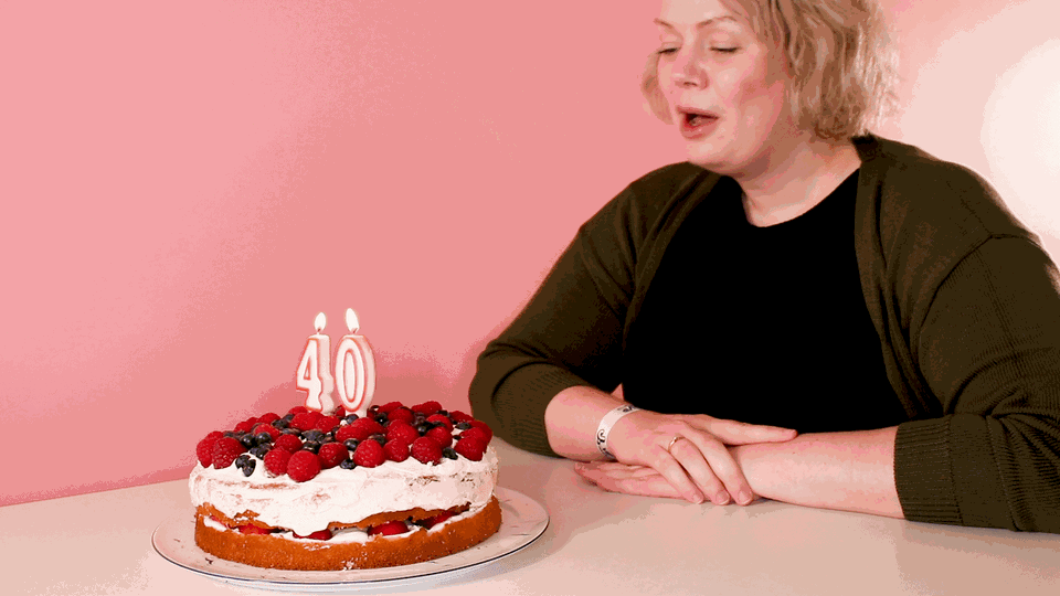 40 werden: Eine Frau pustet Kerzen auf einem Kuchen aus