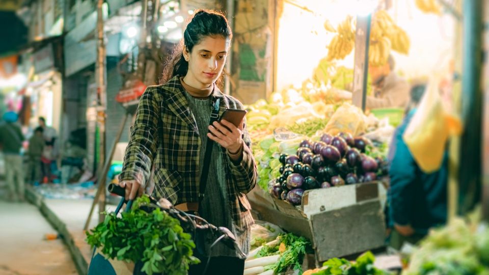 Eine Frau schaut auf einem Markt mit ernstem Blick auf ihr Handy