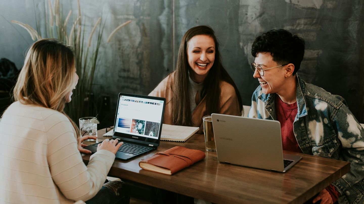Jugendlich aussehende Menschen an einem Tisch mit Laptops