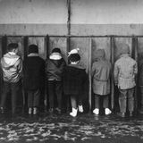 Kleine Jungen stehen an einer abgeteilten Wand, um zu pinkeln