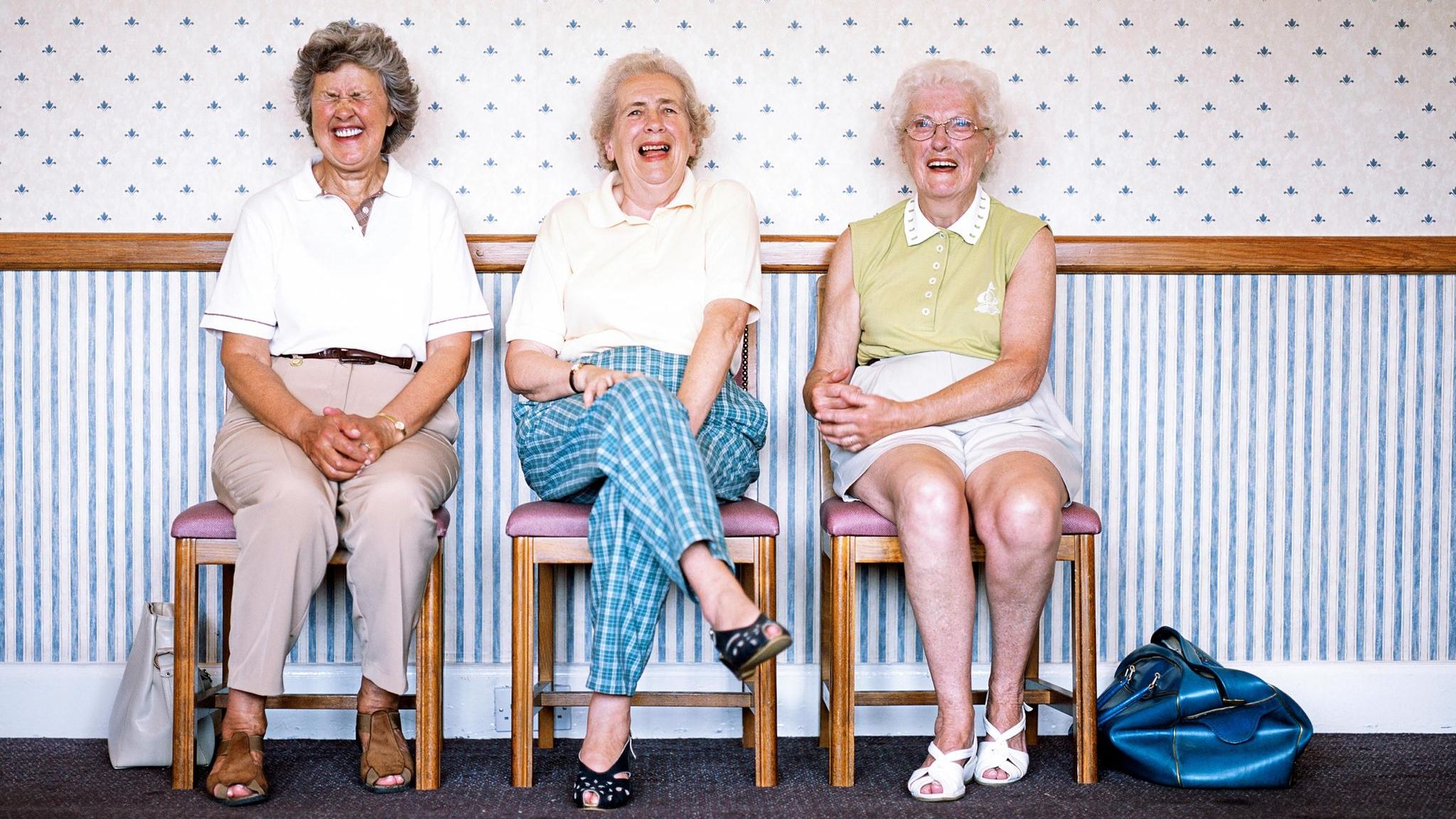 Besser Altern: Drei Seniorinnen sitzen lachend nebeneinander