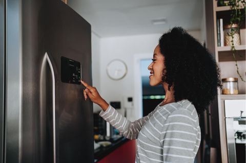 Smarte Küche: Frau programmiert das Display ihres smarten Kühlschranks.