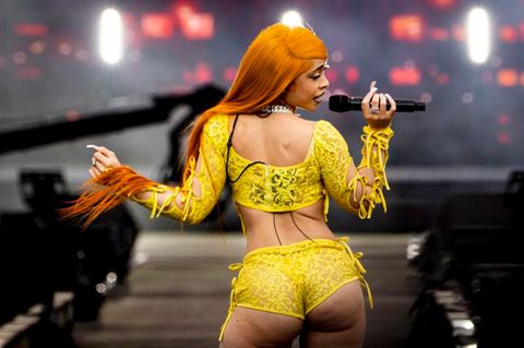 Rapperin Ice Spice mit Perücke in Orange und Hotpans aus gelber Spitze auf der Bühne