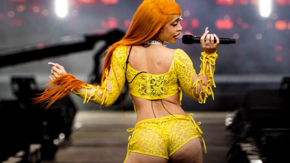 Rapperin Ice Spice mit Perücke in Orange und Hotpans aus gelber Spitze auf der Bühne