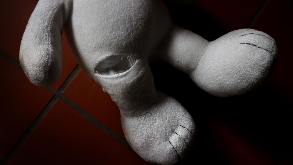 Ein Teddybär mit einem Riss im Bein auf roten Fliesen