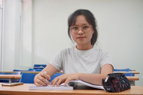 Junge Frau mit Brille sitzt am Schreibtisch