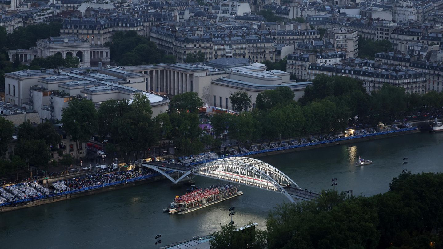 Die Fußgängerbrücke Passerelle Debilly leuchtet in der beginnenden Dämmerung, darunter ist das Boot mit der spanischen und der estnischen Mannschaft zu sehen