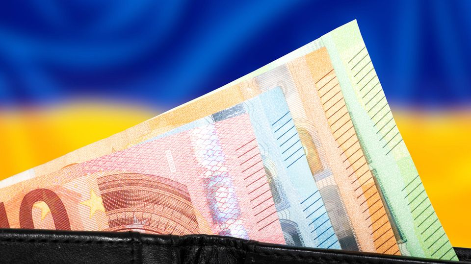 Bündel Euroscheine vor einer unscharfen Ukraine-Flagge