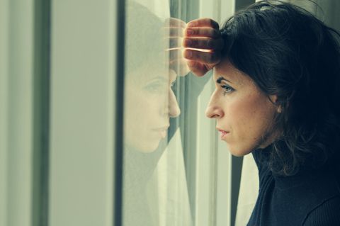Symbolbild Hochbegabung: Eine Frau lehnt ihr Gesicht gegen eine Scheibe und guckt nach draußen