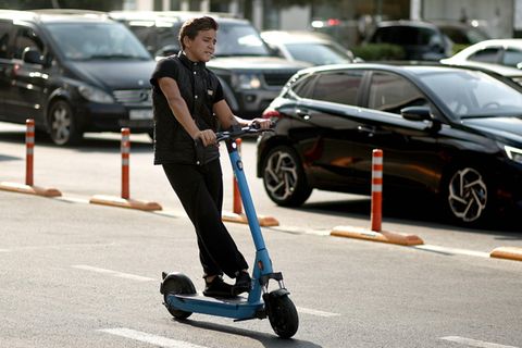 Ein Junge brettert mit einem E-Scooter an einer dicht befahrenen Straße vorbei
