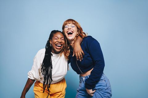 Bebilderung Freundschaft: Zwei junge Frauen liegen sich in den Armen und lachen