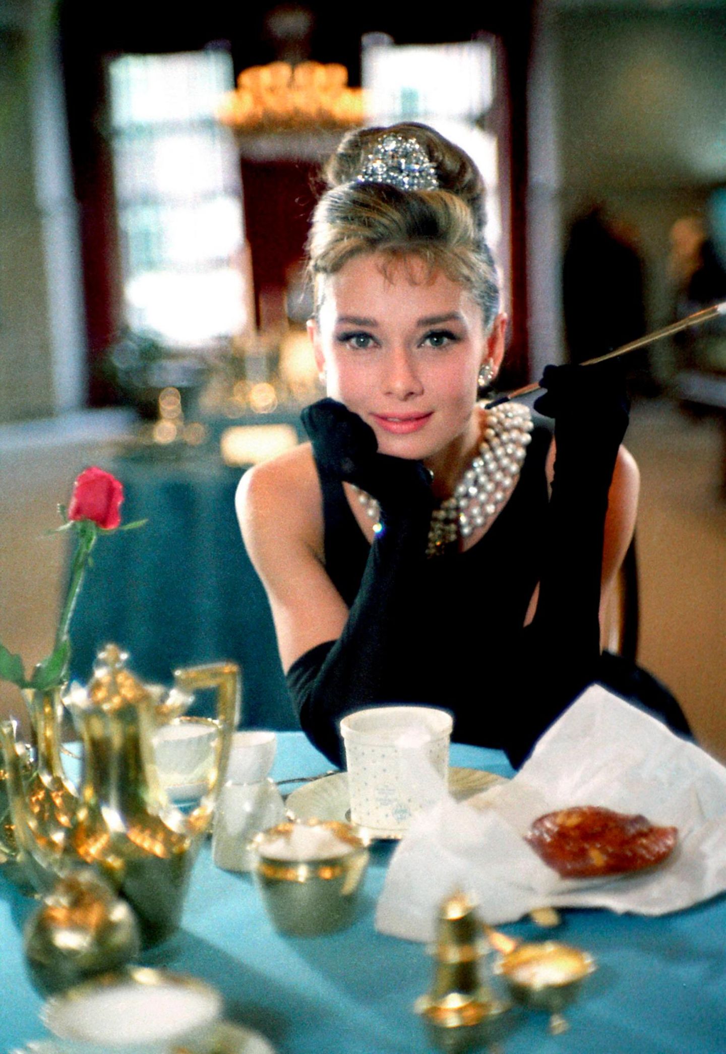 Audrey Hepburns sitzt im schwarzem Kleid mit einer Zigarette in der Hand an einem gedecktem Tisch Audrey Hepburns sitzt im schwarzem Kleid mit einer Zigarette in der Hand an einem gedecktem Tisch