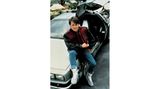 Michael J. Fox sitzt lässig auf dem Auto aus "Zurück in die Zukunft" und guckt in die Kamera