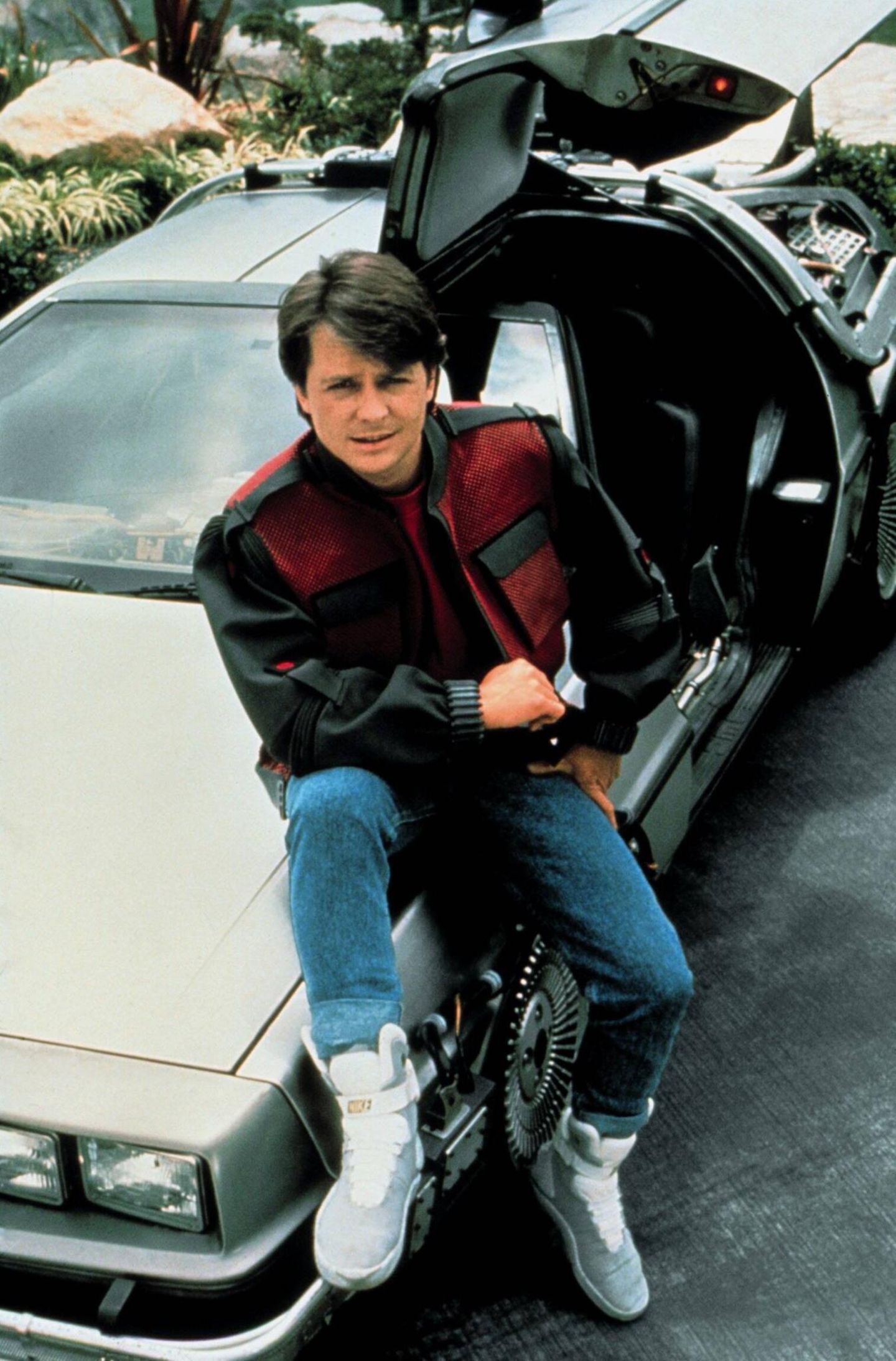 Michael J. Fox sitzt lässig auf dem Auto aus "Zurück in die Zukunft" und guckt in die Kamera Michael J. Fox sitzt lässig auf dem Auto aus "Zurück in die Zukunft" und guckt in die Kamera