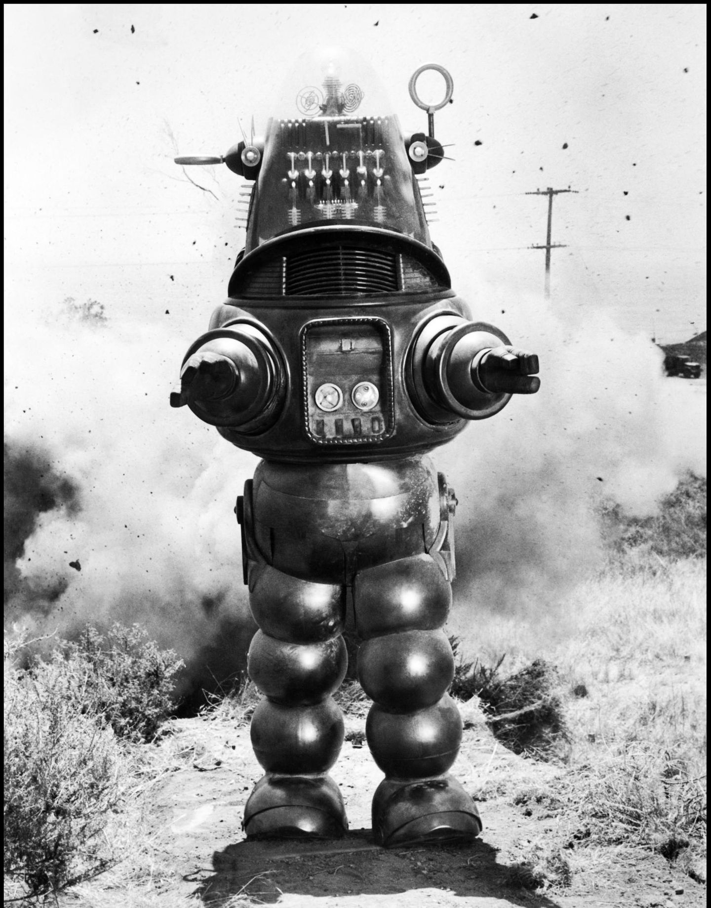 Robby der Roboter steht frontal mit ausgestreckten Armen in der Öde. Robby der Roboter steht frontal mit ausgestreckten Armen in der Öde.