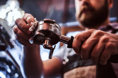 Siebträgermaschine reinigen: Barista säubert einen Siebträger