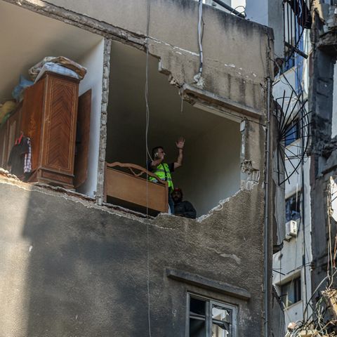 Mitarbeiter des Zivilschutzes inspizieren eine zerstörte Wohnung in einem halb zerstörten Gebäude