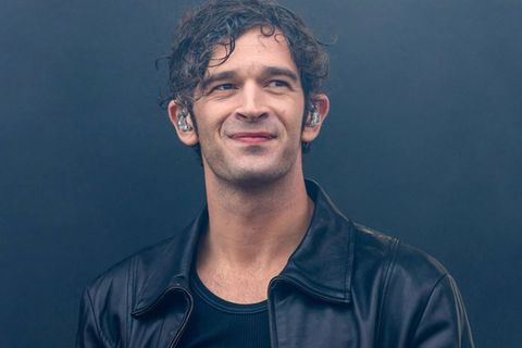 Matty Healy, Sänger der Band The 1975, steht mit Monitor-Kopfhörern auf der Bühne