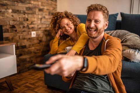 Waipu.tv-Sommer-Deal mit Paramount+: Junges Pärchen sitzt lachend vor dem TV.