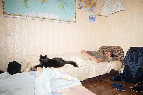 Stephan Orth schläft auf einer Couch an seinen Füßen eine große schwarze Katze