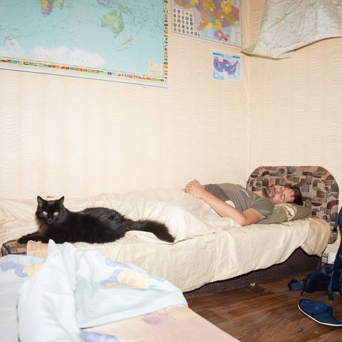 Stephan Orth schläft auf einer Couch an seinen Füßen eine große schwarze Katze