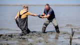 Hilgenriedersiel, Deutschland. Johannes Meyer (r.) hilft Germanus Kettl, Azubi aus Nürnberg, aus dem Schlick im Wattenmeer. Regelmäßig kommen Wasserbau-Lehrlinge aus allen Teilen Deutschlands nach Ostfriesland, um Aufgaben im Küstenschutz kennen zu lernen