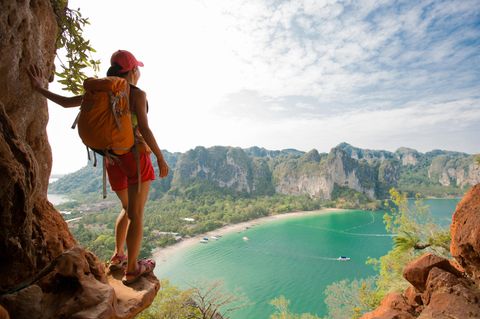 Reiseführer für Thailand: Eine Rucksacktouristin steht auf einem Berg und schaut auf das Meer.