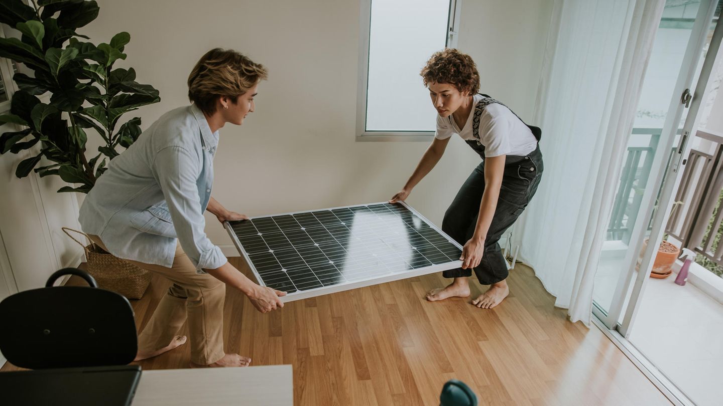 Ein junges Paar trägt Solaranlage durch die Wohnung zur Installation auf dem Balkon