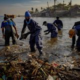 Wegen des ausgelaufenen Öls waten die Helfer mit Schutzkleidung durchs Wasser