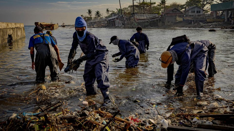 Wegen des ausgelaufenen Öls waten die Helfer mit Schutzkleidung durchs Wasser