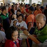 Menschen drängen sich an einer Versorgungsstelle, wo Helfer Nahrung und Trinken ausgeben