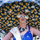 Ein Mannin Frauenkleidung mit einem riesigen Hut