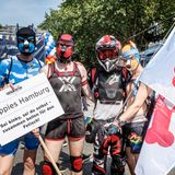 Vier Männer mit Hundemasken und Plakat