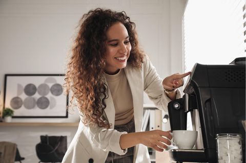 Kaffeevollautomat: Frau macht sich einen Kaffee per Knopfdruck.