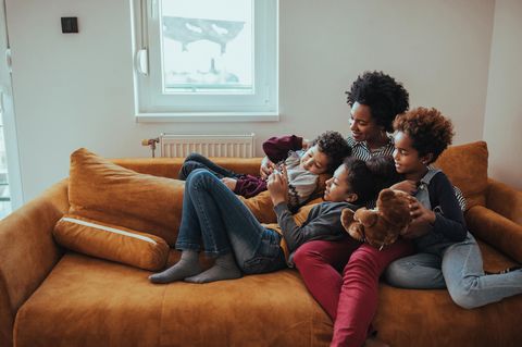 Eine Mutter spielt mit ihren drei Kindern auf dem Sofa