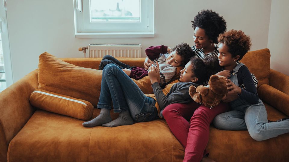 Eine Mutter spielt mit ihren drei Kindern auf dem Sofa