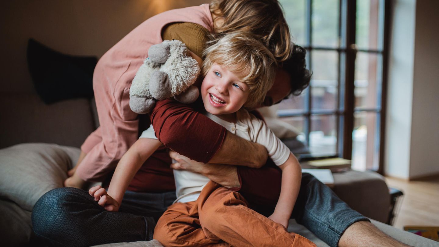 Ein Vater turnt mit seinen zwei kleinen Kindern auf dem Sofa