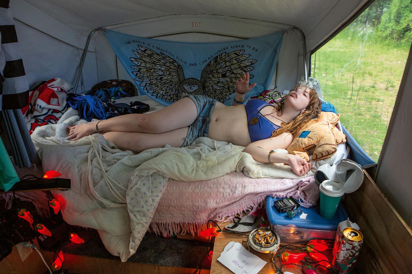 Jessica liegt rauchend in einem Zelt auf ihrem Bett. Jessica liegt rauchend in einem Zelt auf ihrem Bett.