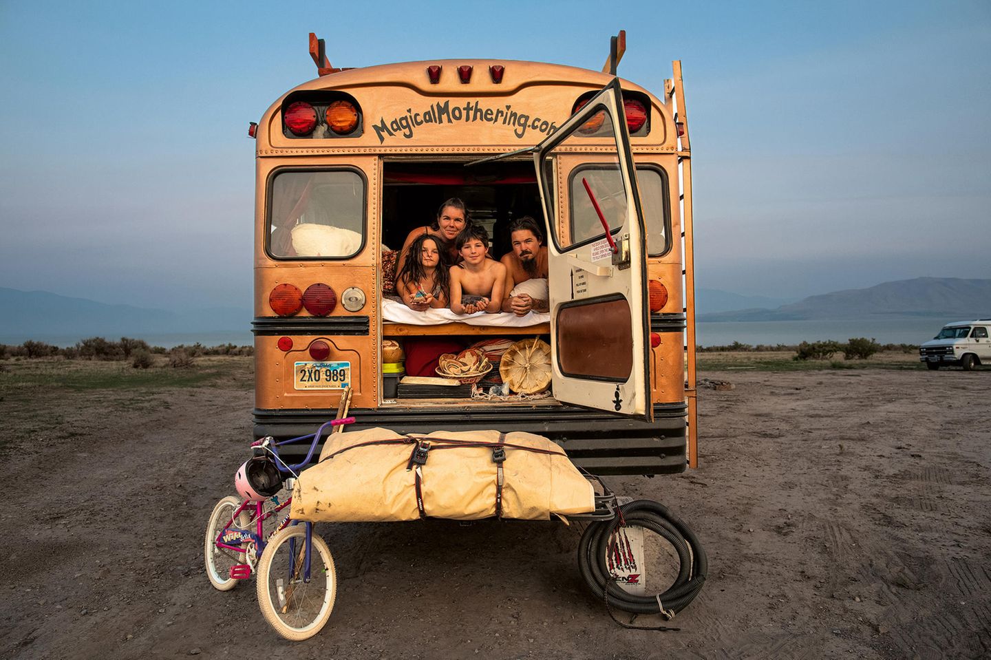 Eine Familie schaut aus der Hintertür eines umgebauten, amerikanischen Schulbusses. Eine Familie schaut aus der Hintertür eines umgebauten, amerikanischen Schulbusses.