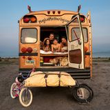 Eine Familie schaut aus der Hintertür eines umgebauten, amerikanischen Schulbusses.