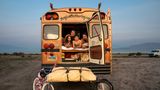 Eine Familie schaut aus der Hintertür eines umgebauten, amerikanischen Schulbusses.