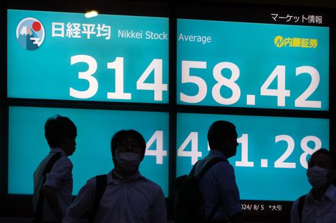 Die Konturen von Männern sind vor einem Bildschirm mit dem Nikkei an der Börse von Tokio zu sehen