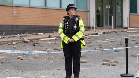 Eine Polizistin steht vor einem Hostel, das ein rechter Mob attackiert hat