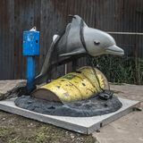 Delfin in Öl  Was sehen wir? Natürlich kein Ölgemälde von Flipper, sondern eine Kirmesattraktion für Kinder: ein Delfin zum Reiten – aber verheddert in einem Fischernetz und umgeben von Erdöl. Woher das kommt, daran lässt Banksy keinen Zweifel. Auf dem Fass prangt groß das Firmenlogo des Energiekonzerns BP (British Pertroleum).  Was will uns Banksy damit sagen? Er stellte seinen Flipper 2013 ausgerechnet an der Promenade im britischen Seebad Brighton auf, wo täglich Tausende Touristen entlangschlendern. Das Ding ratterte dort pausenlos vor sich hin – üblicherweise muss man eine Münze einwerfen – und lockte so zahllose Kinder an. Was zu einigen Fragen geführt haben muss: "Mama, warum guckt der Delfin so traurig?" – "Papa, wer ist BP und was machen die?" – "Mama, warum ist BP so böse?" Noch Fragen, was uns Banksy sagen will?